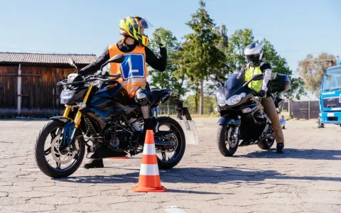 Nauka jazdy na motocyklu. Kursant w kamizelce z literą "L" i kasku na motocyklu, gotowy do zdobycia prawko na motocykl.