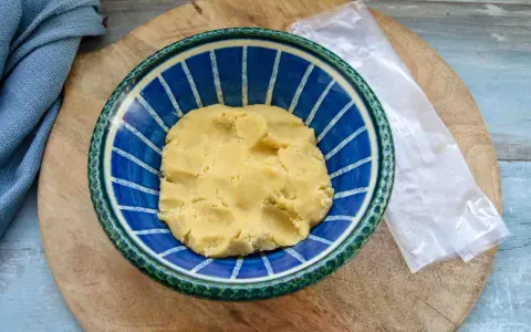 Frischer quiche teig in einer blauen Schüssel, bereit für die Zubereitung einer herzhaften Quiche.