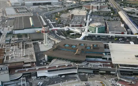 Widok z lotu ptaka na lotnisko Rzym Fiumicino z wieżą kontroli lotów, terminalami i drogami.