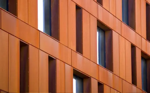 Fachada de edificio revestida con paneles de acero corten, creando un efecto oxidado y moderno.
