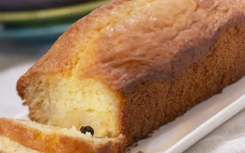 Un cake doré, parfait pour une recette facile. Deux tranches sont coupées, révélant une mie moelleuse et quelques raisins secs.