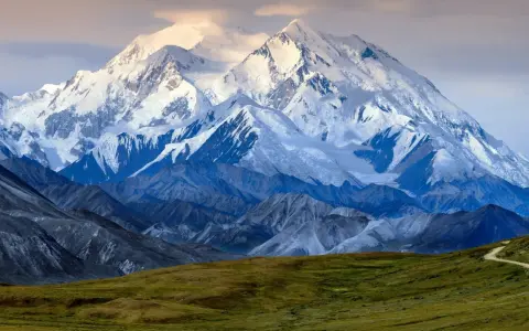 Majestatyczny, ośnieżony szczyt Denali, jednego z najwyższych szczytów kontynentów, góruje nad surowym krajobrazem.