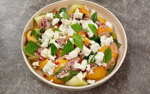 En uppfriskande melon och fetaostsallad med basilika och rödlök. Perfekt sommarbuffé.