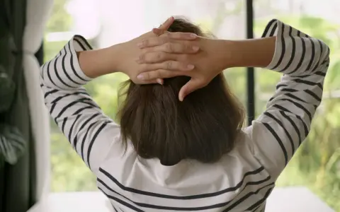 En person med händerna bakom huvudet, klädd i en randig tröja, tar en stund att hitta tillbaka efter paus.
