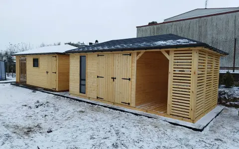 Drewniana altana z ażurowymi ścianami i solidnym dachem, obok budynek gospodarczy.