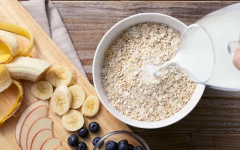 Haferflocken mit Milch, geschnittener Banane, Äpfeln und Blaubeeren. Eine gesunde Mahlzeit, die hilft, Cholesterin zu senken.