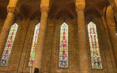 Vitraux colorés illuminant l'intérieur de l'église de Gien, encadrés par de hautes colonnes de briques.