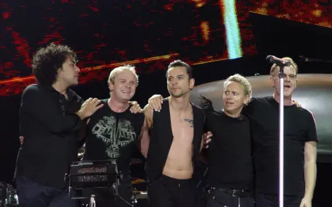 Les membres de Depeche Mode sur scène, souriants et complices, profitent de l'instant.