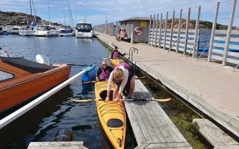 Förberedelser för kajakpaddling i Lysekil. En gul kajak ligger i vattnet vid en brygga, redo för äventyr.