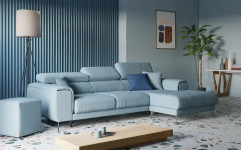 Accogliente soggiorno con divano angolare azzurro, tavolino in legno, lampada da terra e pianta.