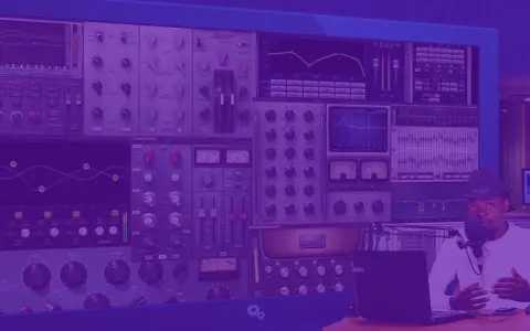 Un homme au chapeau parle dans un micro, entouré d'écrans affichant des logiciels pour faire des prods musicales.