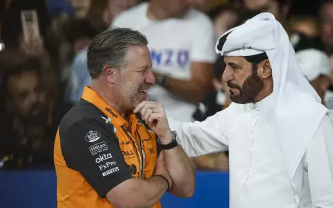 Mohammed Ben Sulayem, con túnica blanca, conversa animadamente con un hombre con polo naranja de McLaren.