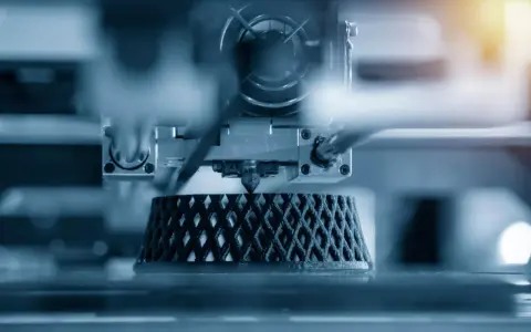 Close-up of an advanced 3D printing machine creating a complex, lattice-like object layer by layer.