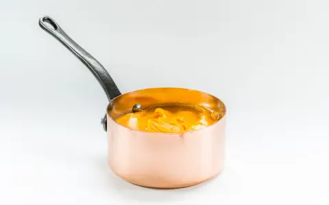Cazo de cobre con puré de boniato cremoso y naranja, listo para servir.