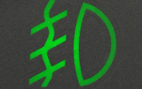 Zielony symbol przeciwmgielny na ciemnym tle.