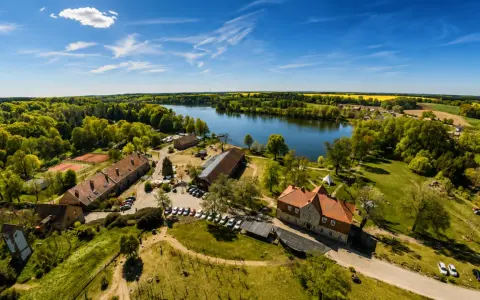 Agroturystyka nad jeziorem, gdzie można podziwiać piękne krajobrazy i odpocząć. W oddali widać pola rzepaku.