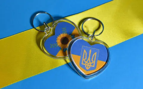Dos llaveros en forma de corazón con la bandera de Ucrania. Uno tiene un girasol, el otro el escudo. Ideas para como hacer llaveros personalizados.