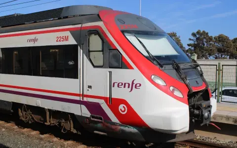 Czoło pociągu Renfe 225M z czerwonymi i białymi pasami, stojącego na torach.