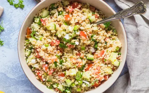 Frischer bulgur salat mit Tomaten, Gurken und Frühlingszwiebeln, garniert mit Petersilie.