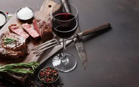 En saftig entrecote, perfekt tillagad, med ett glas rött vin. Kryddor och rosmarin fulländar upplevelsen.