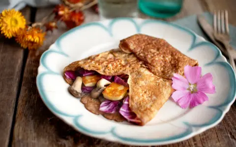 Matiga pannkakor fyllda med svamp, halloumi och rödkål, dekorerade med en rosa blomma.