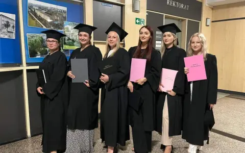 Absolwentki studiów w Raciborzu w togach i biretach z pracami licencjackimi.