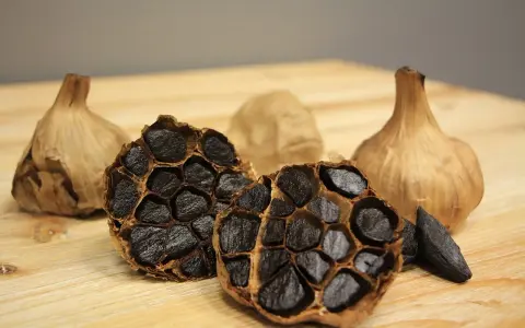 Ajos negros enteros y cortados, mostrando sus dientes oscuros y arrugados. Descubre las increíbles ajo negro propiedades.