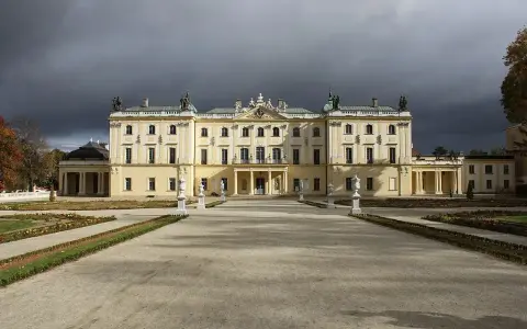 Pałac Branickich w Białymstoku, majestatyczna budowla z ogrodem, pod burzowym niebem.