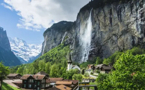 Lauterbrunnen Wasserfall stürzt von einer Felswand, umgeben von einem Dorf und schneebedeckten Bergen.