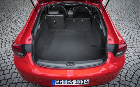 Czerwony Opel Insignia z otwartym bagażnikiem. Duża przestrzeń ładunkowa, idealna na wakacyjne wyjazdy. Sprawdź opel insignia pojemność bagażnika.