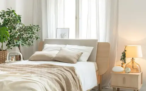 Przytulna sypialnia inspiracje: łóżko z beżowym zagłówkiem, biała pościel, narzuta w jodełkę, rośliny, lampka nocna.