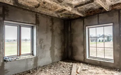 Wnętrze w budowie, dwa okna wychodzą na pola. Odległość okna od granicy działki i zgoda sąsiada to kluczowe kwestie przy planowaniu.