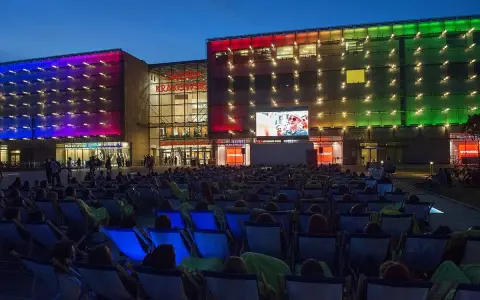 Wieczorny seans pod gołym niebem przed Galerią Krakowską. Tłum widzów w leżakach ogląda film na wielkim ekranie.