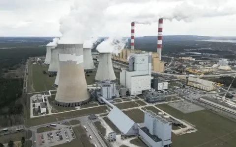 Große Kühltürme und Schornsteine einer polnischen Kraftwerksanlage, die Dampf abgeben. Der Strommix Polens wird hier sichtbar.