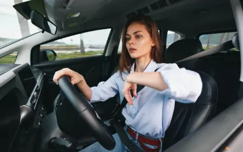 Kobieta za kierownicą zastanawia się, czy OC przedłuża się automatycznie. Widok na morze i palmy.