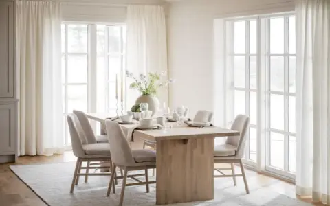 Ljust och luftigt kök med ett träbord dukat för middag. Inspiration dekoration matbord med en stor vas med blommor och ljus.