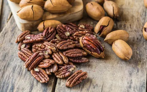 Noix de pécan décortiquées et entières sur fond de bois. Découvrez le noix de pécan bienfait pour une alimentation saine et gourmande.