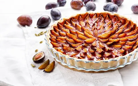Une délicieuse tarte aux prunes, garnie de fruits frais et dorés, prête à être dégustée.