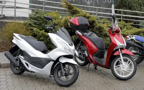 Biały i czerwony skuter stoją na mokrym bruku. Zastanawiasz się, ile oleju do skutera 4t?