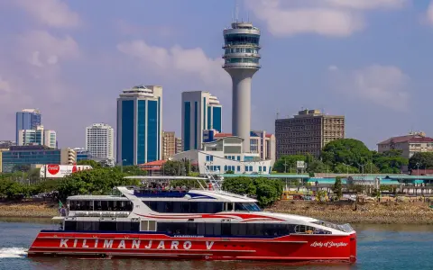Prom na Zanzibar, "Kilimanjaro V", płynie przy nowoczesnej panoramie Dar es Salaam Tanzania, z charakterystyczną wieżą kontroli lotów.