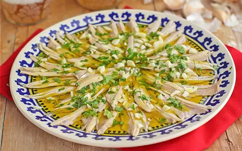Boquerones en vinagre, un plato fresco y sabroso, servido en una fuente decorada con perejil y ajo picado.