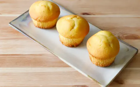 Tre soffici muffin allo yogurt dorati, pronti per essere gustati su un piatto rettangolare.