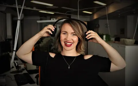 Uśmiechnięta kobieta w słuchawkach, gotowa do nagrania podcastu po angielsku.