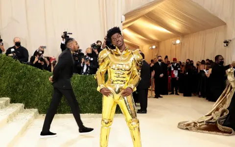 Lil Nas X, un caballero dorado, posa en la alfombra de la Met Gala, rodeado de fotógrafos y admiradores.