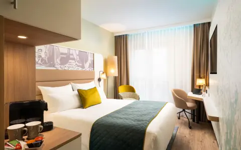 Modern Hotelzimmer mit Bett, Schreibtisch und Kaffeemaschine.
