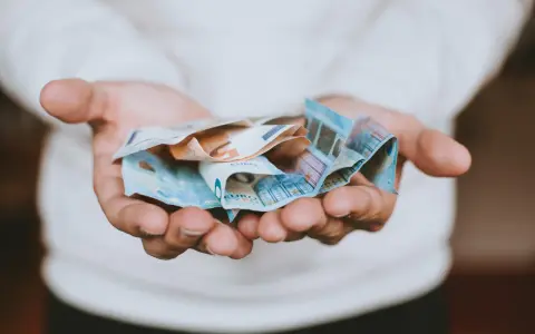 Dłonie trzymające banknoty euro, symbolizujące opłatę za pełnomocnictwo.