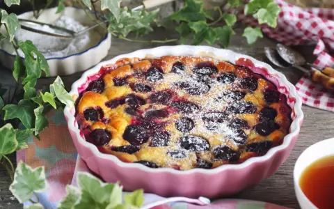 Un délicieux clafoutis aux prunes, saupoudré de sucre glace, prêt à être dégusté.