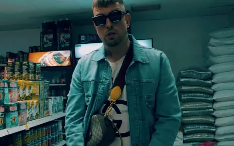 Malik Sentino w okularach i dżinsowej kurtce stoi w sklepie, otoczony towarem.