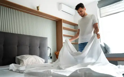 Hombre cambiando sábanas, un paso clave para saber como quitar acaros del colchon y mantener un ambiente fresco y saludable.