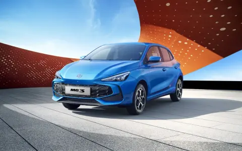 Niebieski MG3 Hybrid stoi na tle nowoczesnej architektury i błękitnego nieba.